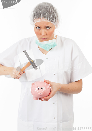 Image of a woman doctor breaks his piggy bank with a hammer