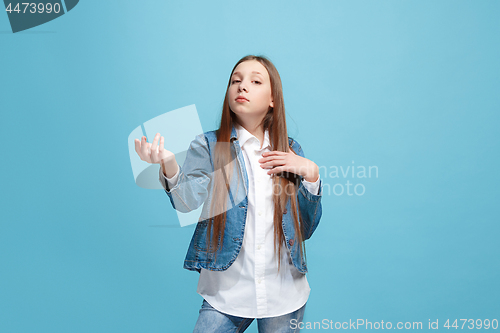 Image of Beautiful female half-length portrait on blue studio backgroud. The young emotional teen girl