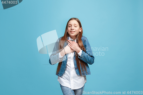 Image of The happy teen girl standing and smiling against blue background.