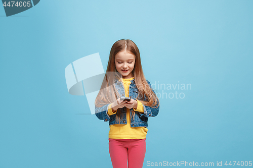 Image of The happy teen girl standing and smiling against blue background.