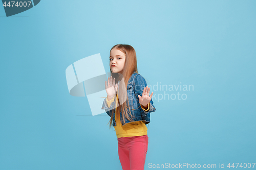 Image of Doubtful pensive teen girl rejecting something against blue background