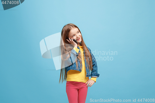 Image of The happy teen girl standing and smiling against blue background.