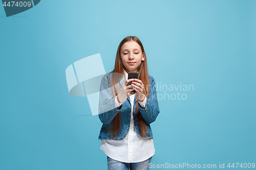 Image of The happy teen girl standing and smiling against blue background.