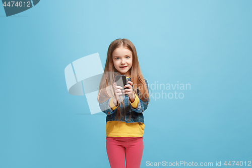 Image of The happy teen girl standing and smiling against blue background.