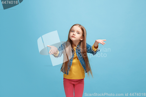 Image of Beautiful female half-length portrait on blue studio backgroud. The young emotional teen girl