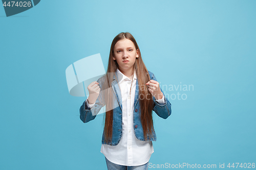 Image of Portrait of angry teen girl on a blue studio background