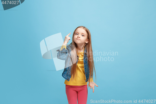 Image of Beautiful female half-length portrait on blue studio backgroud. The young emotional teen girl