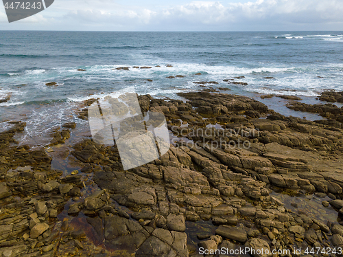 Image of Aerial view of ocean waves and rocky coast