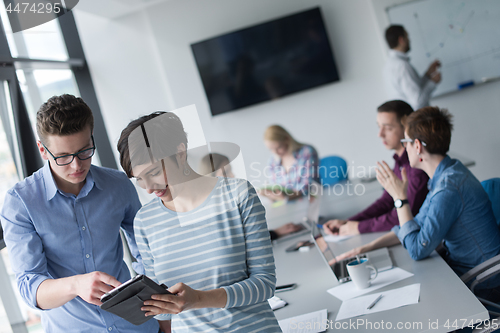 Image of Two Business People Working With Tablet in office