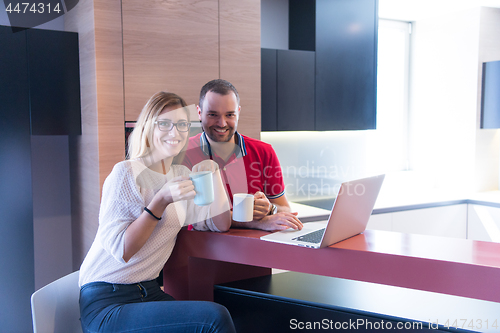 Image of couple drinking coffee and using laptop at home