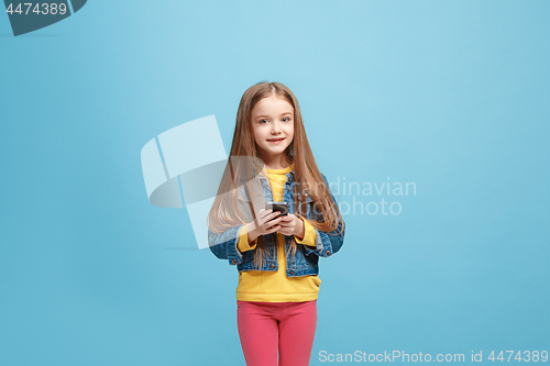 Image of The happy teen girl standing and smiling against blue background.