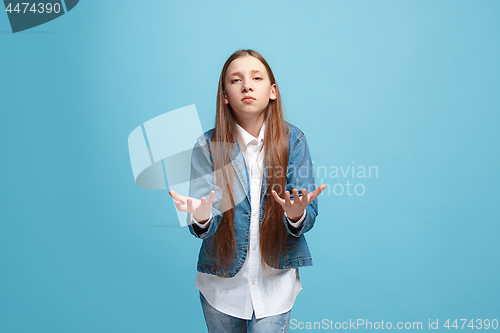 Image of Beautiful female half-length portrait on blue studio backgroud. The young emotional teen girl