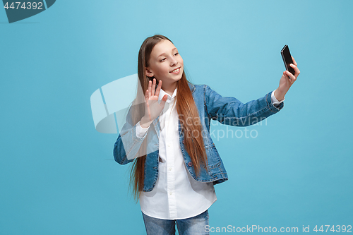 Image of The happy teen girl standing and smiling against pink background.