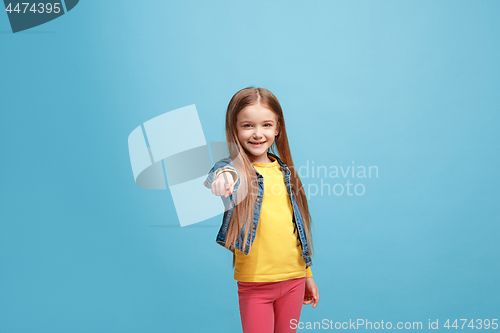 Image of The happy teen girl pointing to you, half length closeup portrait on blue background.
