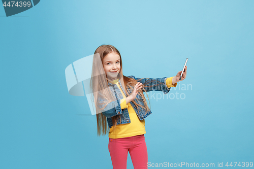 Image of The happy teen girl standing and smiling against blue background.