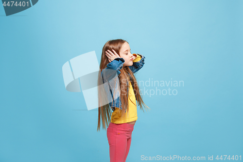 Image of Beautiful female half-length portrait on blue studio backgroud. The young emotional teen girl