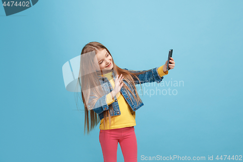 Image of The happy teen girl standing and smiling against blue background.