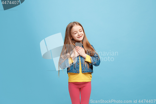 Image of The happy teen girl standing and smiling against blue background.