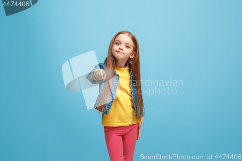 Image of The happy teen girl pointing to you, half length closeup portrait on blue background.