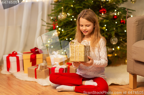 Image of smiling girl with christmas gift at home