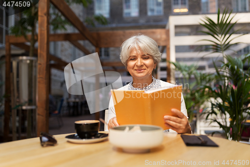 Image of senior woman with coffee at street cafe