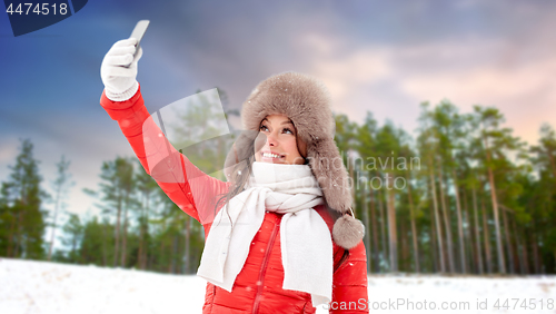 Image of happy woman taking selfie over winter forest