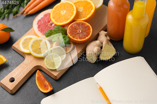 Image of close up of fruits, juices and notebook on table