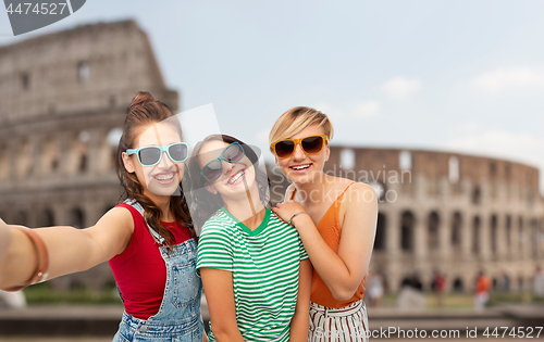 Image of happy female friends taking selfie over coliseum