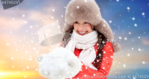 Image of happy woman with snow in winter fur hat outdoors