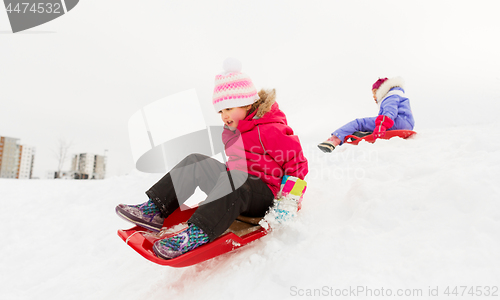 Image of happy little girl sliding down on sled in winter
