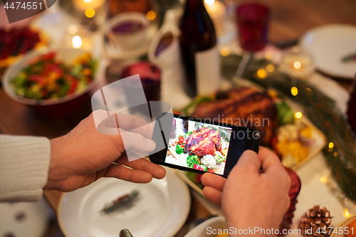 Image of hands photographing food at christmas dinner