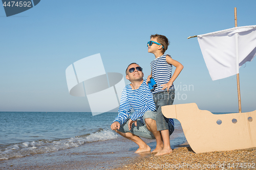 Image of Father and son playing on the beach at the day time.