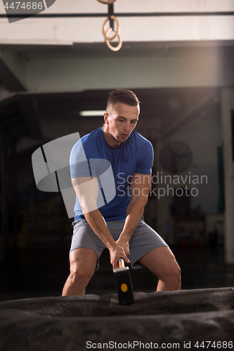 Image of man workout with hammer and tractor tire