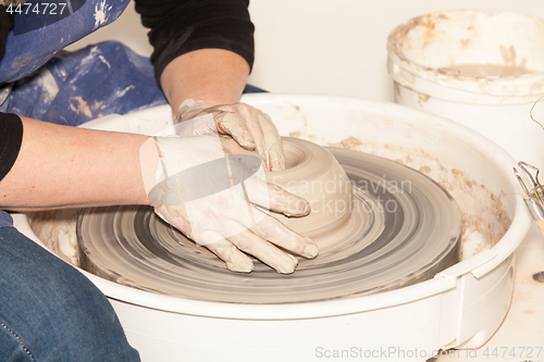 Image of Female Potter creating a earthen jar on a Potter\'s wheel