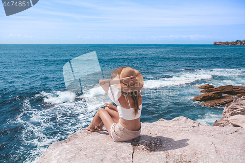 Image of Chic young woman sitting by the ocean.