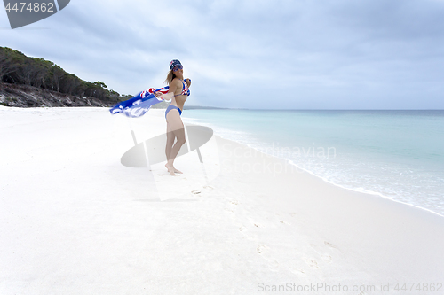 Image of Smiling female holding Australian flag and wearing flag bikini