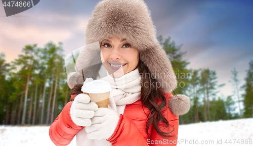 Image of woman in fur hat with coffee over winter forest