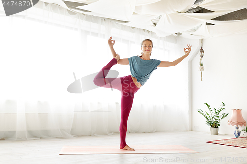 Image of young woman doing yoga one legged pose at studio