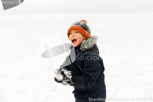 Image of happy little boy playing with snow in winter