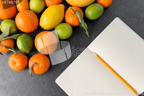 Image of close up of fruits and notebook on slate table top