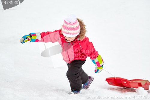 Image of girl with sled climbing snow hill in winter