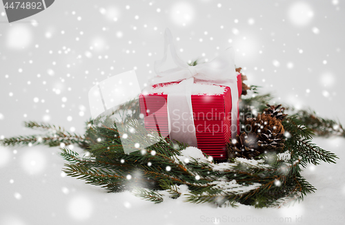 Image of christmas gift and fir wreath with cones on snow