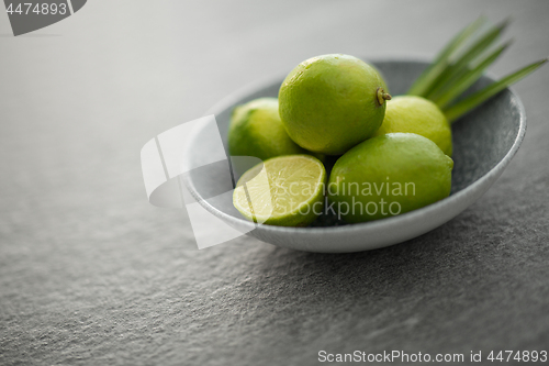 Image of close up of limes in bowl on slate table top