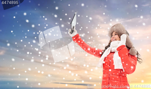 Image of woman in winter fur hat with tablet pc outdoors