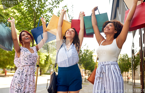 Image of happy women with shopping bags in city