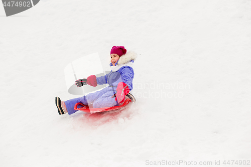 Image of girl sliding down on snow saucer sled in winter