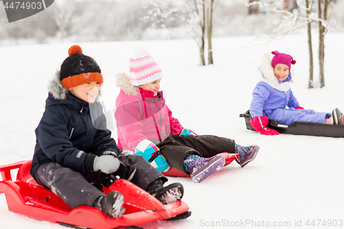 Image of happy little kids sliding on sleds in winter