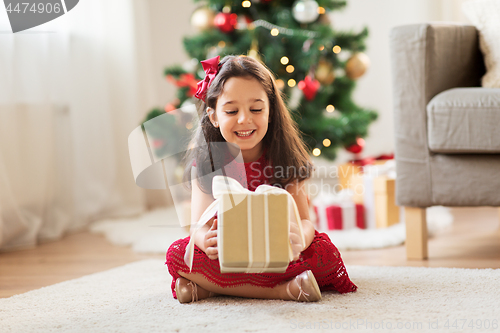 Image of happy girl with christmas gift at home