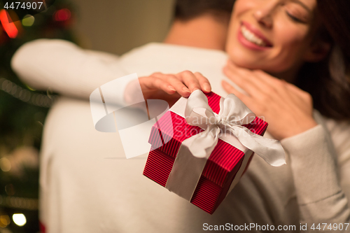 Image of close up of couple with christmas gift hugging