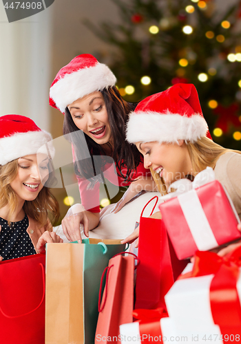 Image of women in santa hats with gifts on christmas